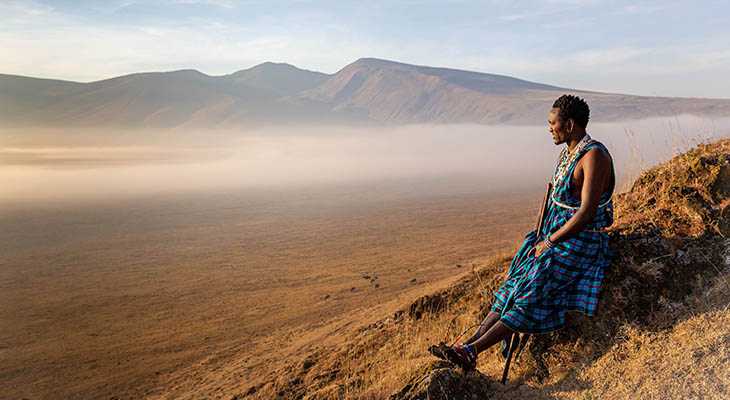 Jonge Masai krijger zittend in de krater van Ngorongoro park kijkend naar zonsopgang