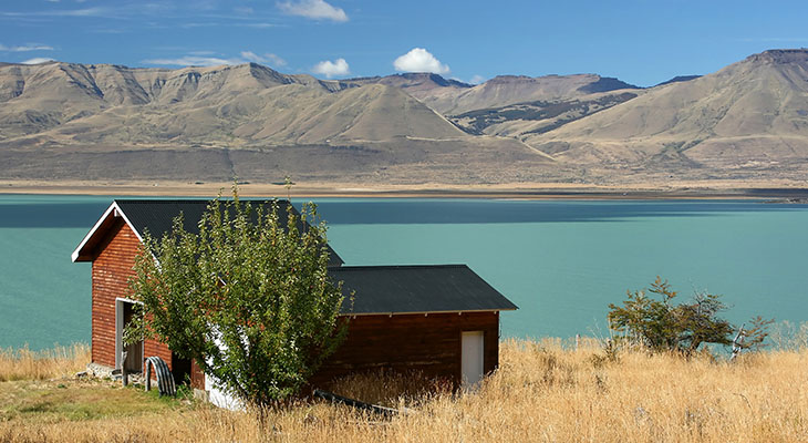 Huis aan een meer met bergen bij El Calafate